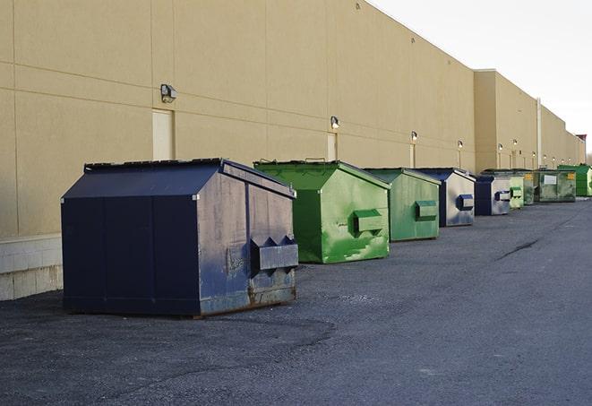 tilted front-load dumpsters being emptied by waste management workers in Bellmore